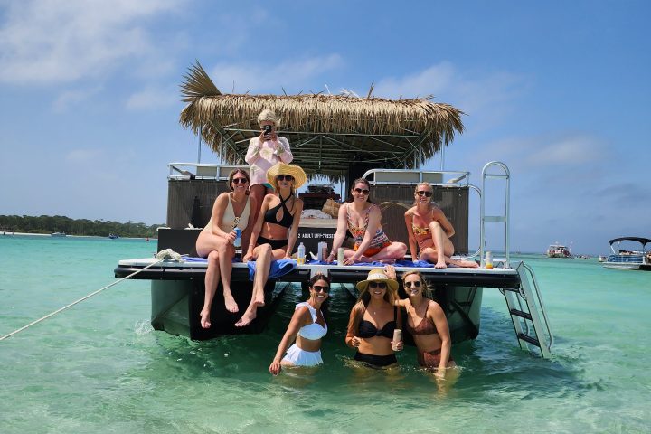 Group of people relaxing on a boat with turquoise water and blue sky background.