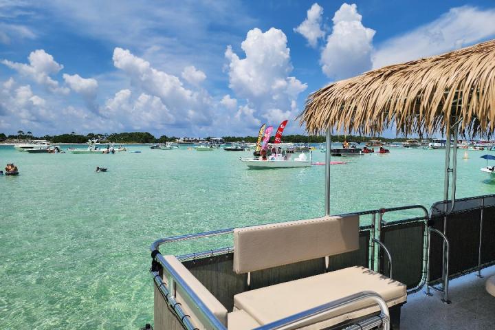 Boats and people on a clear blue sea under a sunny sky with fluffy clouds.